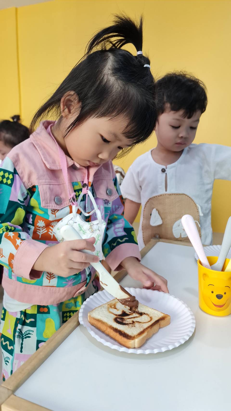 小女孩涂抹面包,参与动手操作课